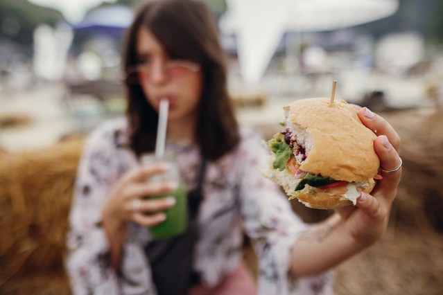 Stylish Hipster Girl Holding Delicious Vegan Burger And Smoothie