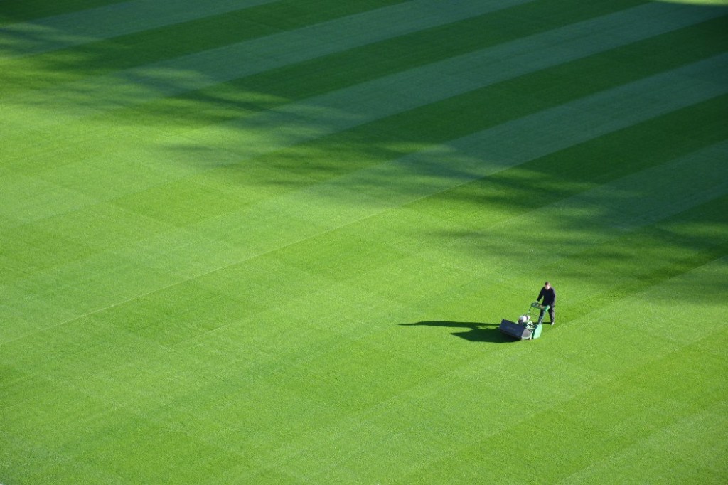 A man is moving a large sports lawn.